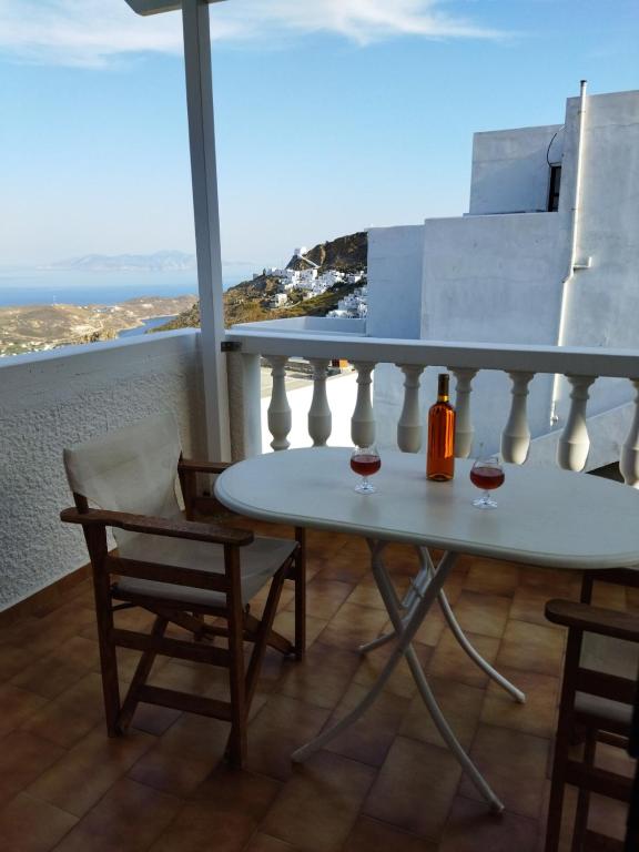 a table with two glasses of wine on a balcony at ANATOLI ROOMS SERIFOs in Serifos Chora
