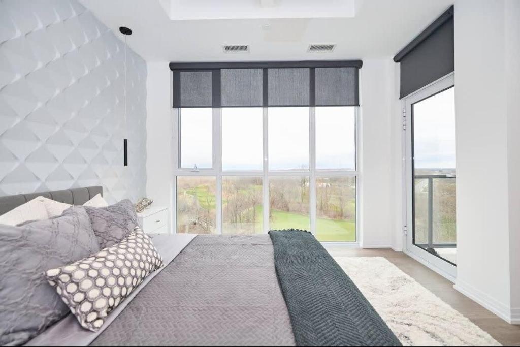 a bedroom with a bed and large windows at Penthouse on the Green in Niagara Falls
