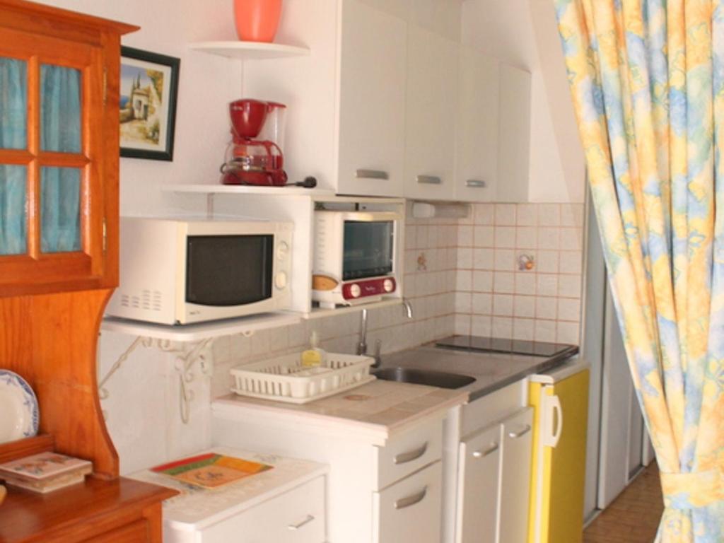 een keuken met witte kasten en een magnetron bij Studio Balaruc-les-Bains, 1 pièce, 3 personnes - FR-1-503-45 in Balaruc-les-Bains