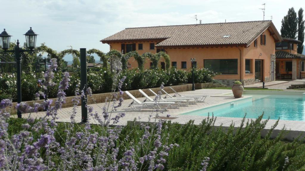 a house with a swimming pool and purple flowers at Il Fienile di Assisi in Assisi