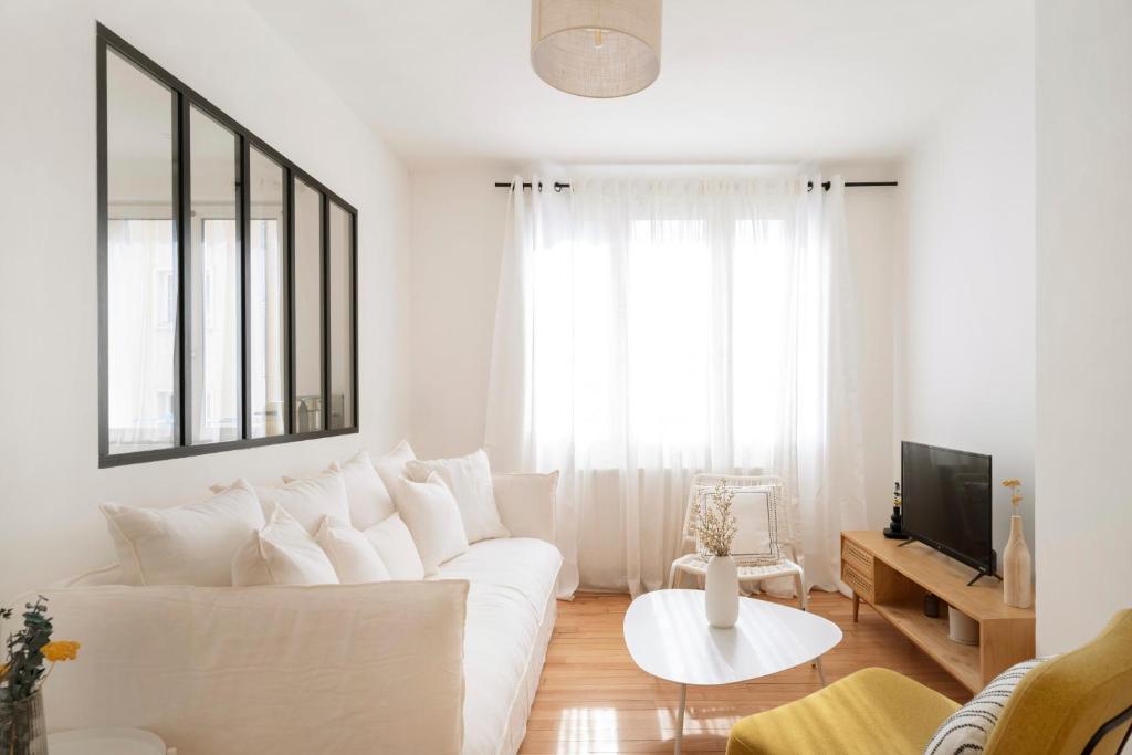 een witte woonkamer met een witte bank en een tv bij Au clair d'Augustin in Metz