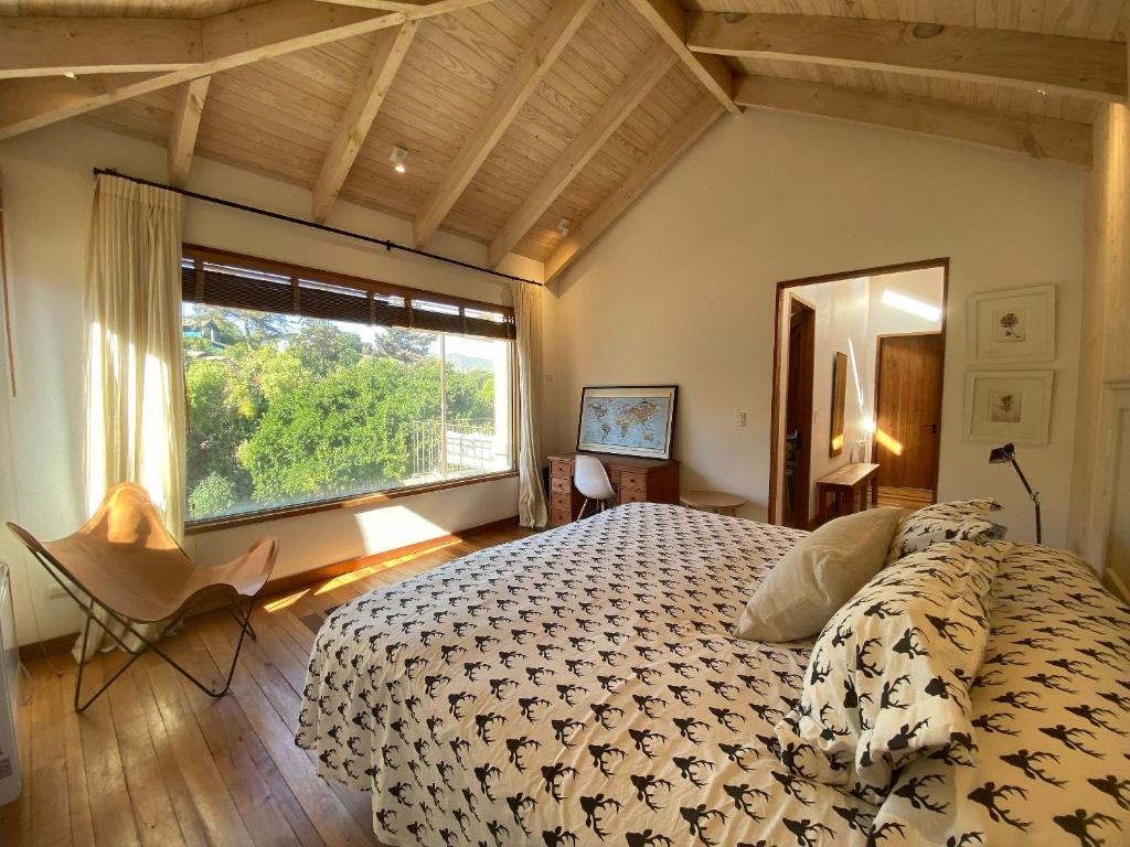 um quarto com uma cama grande e uma janela grande em Amplia casa familiar en Cachagua em Zapallar