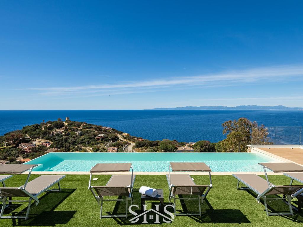 une piscine avec des chaises et l'océan en arrière-plan dans l'établissement Villa Belle View, à Torre delle Stelle