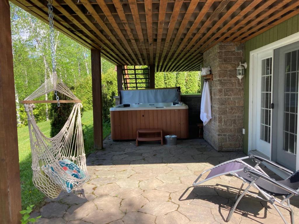 un patio avec un hamac et un bain à remous dans l'établissement Chalet Grand-père Tortue, à Saint-David-de-Falardeau