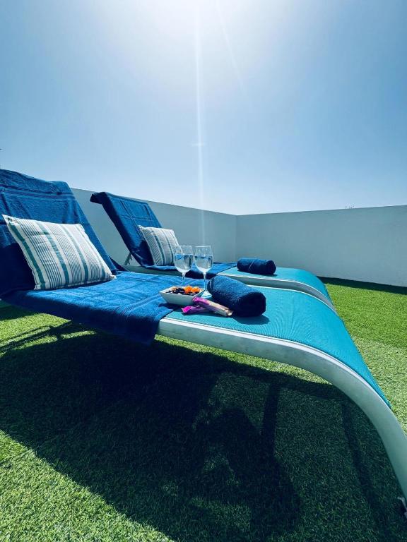 a blue bed with two chairs and glasses on the grass at Lighthouse in Puerto del Rosario