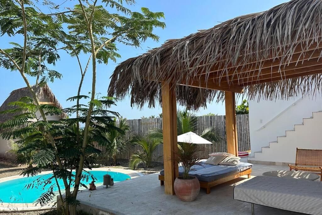 a resort with a swimming pool and a straw umbrella at Las casitas del norte in Zorritos
