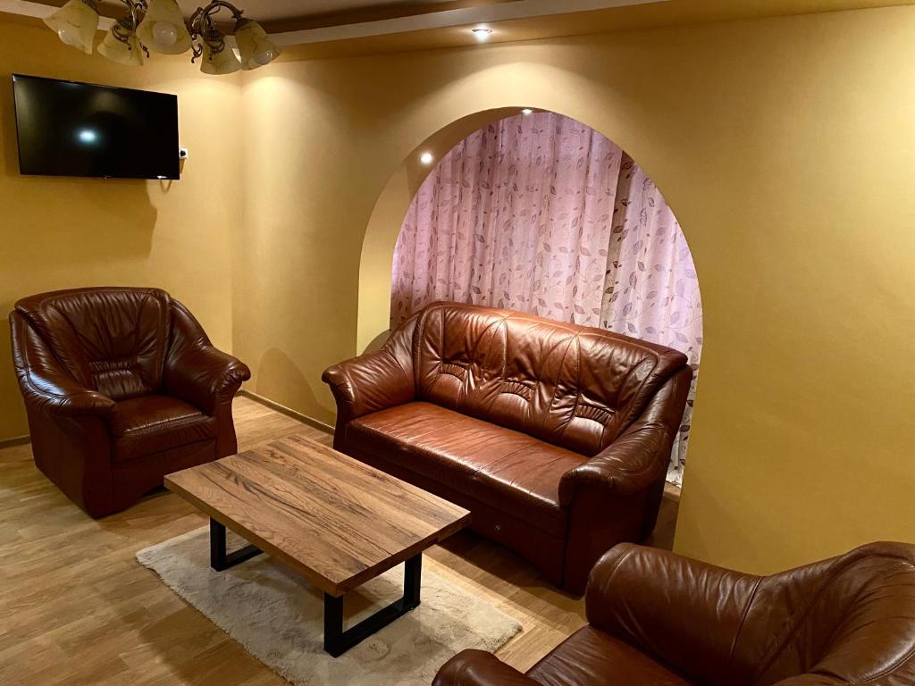 a living room with a leather couch and a table at Apartament lux 3 camere in Roman