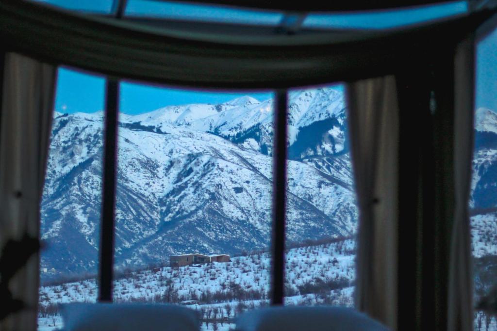 a view of a snow covered mountain through a window at Nature view Almaty in Karagayly