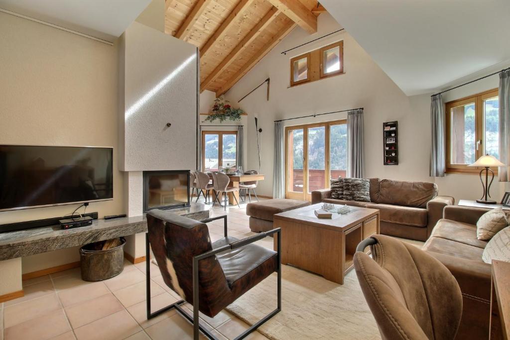 a living room with a couch and a tv at Penthouse With Sunny Balcony And Sauna in Champéry