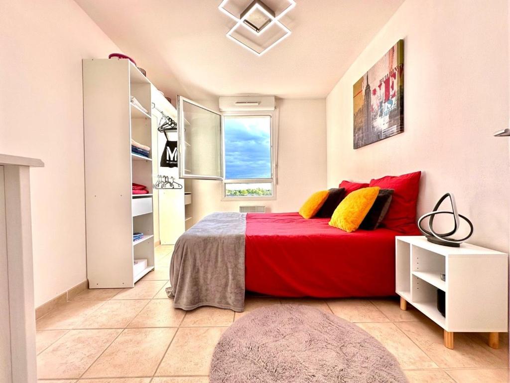 a bedroom with a red bed and a window at L'Écrin Zen, Privé-Parking-CLIM-WIFI-4 pers in Istres