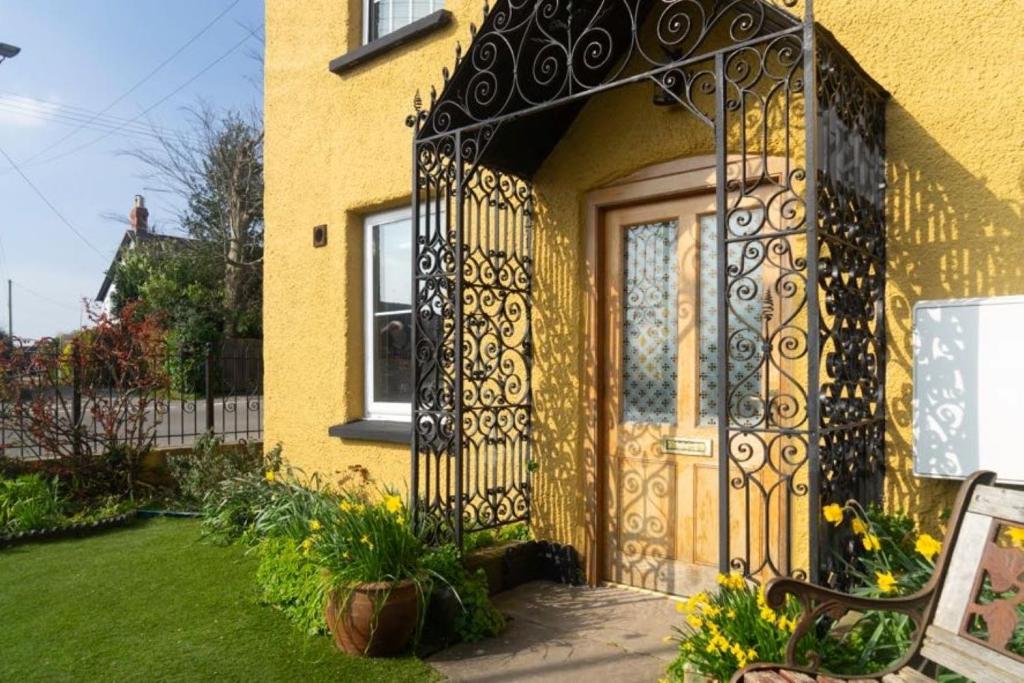 a yellow house with a wrought iron door at Crossways - Eastington in Claypits