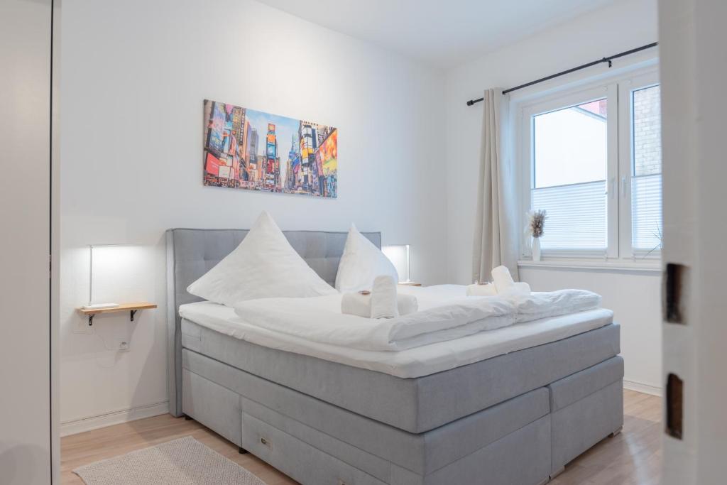 Bett mit weißer Bettwäsche und Kissen in einem Zimmer in der Unterkunft Modernes Apartment 4 Personen Zentral 56qm WLAN gehobene Ausstattung in Hannover