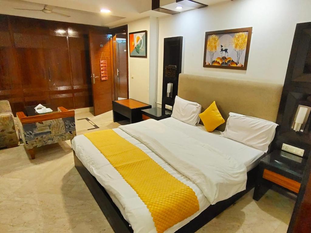 a bedroom with a large bed with yellow and white sheets at Feb Residency in New Delhi