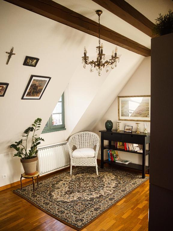 ein Wohnzimmer mit einem Stuhl und einem Kronleuchter in der Unterkunft Gite traditionnel chez Léon Éguisheim in Eguisheim