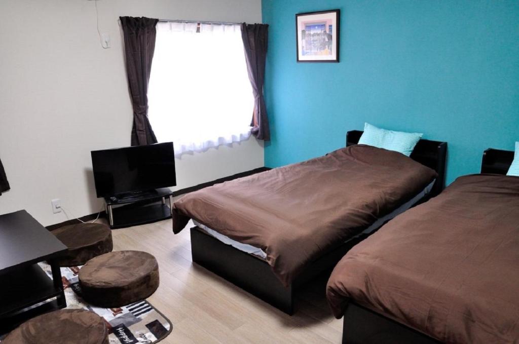 1 Schlafzimmer mit 2 Betten, einem TV und einem Fenster in der Unterkunft Minpaku KEN HOUSE - Vacation STAY 60980v in Nagahama