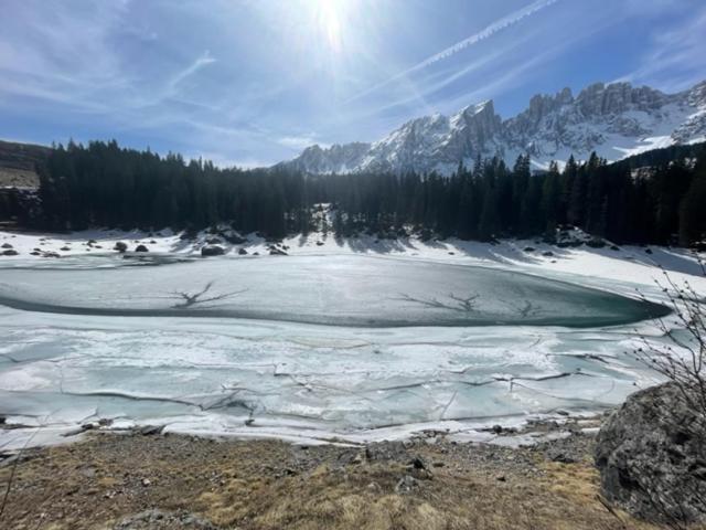 ein gefrorener See mit Schnee und Bergen im Hintergrund in der Unterkunft Splendida Carezza in Karersee