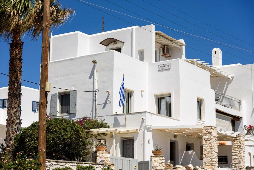 a white building with a palm tree at Zanneta's House in Naousa