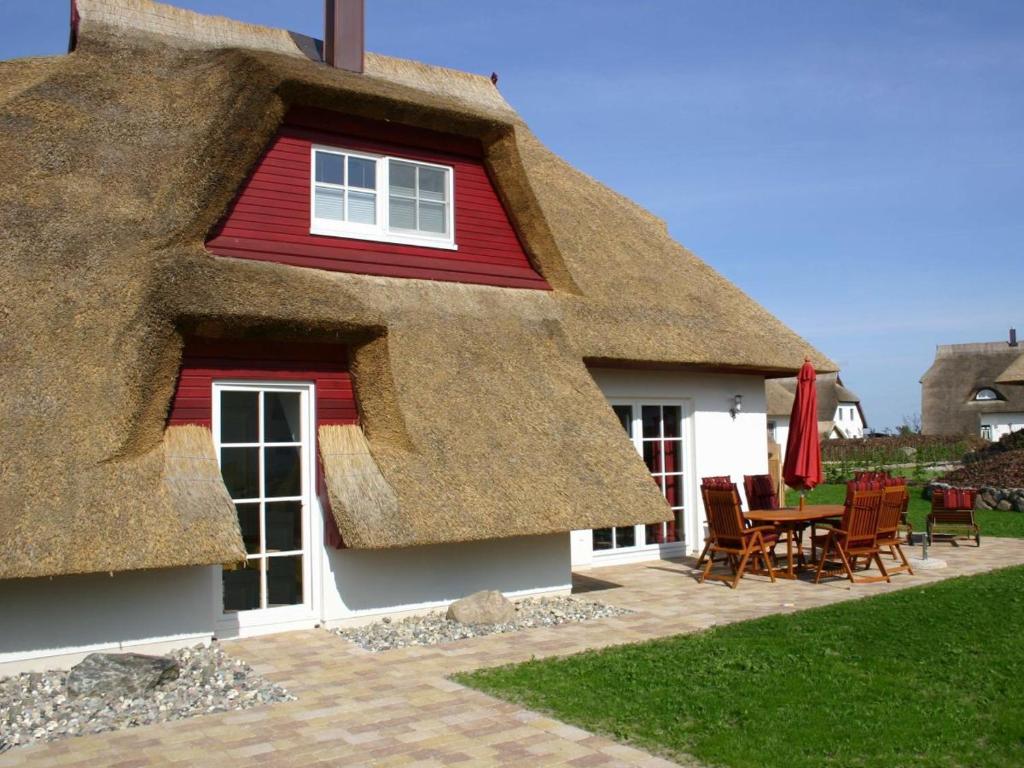 a thatch roofed house with a table and chairs at Villa Butterblume in Zinnowitz