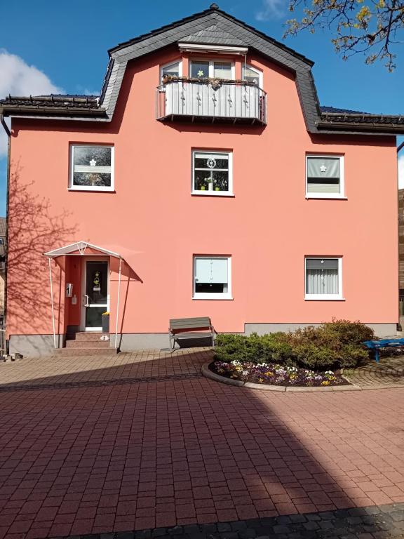 uma casa cor-de-rosa com uma varanda e um banco em Haus Hinzberg em Oberhof