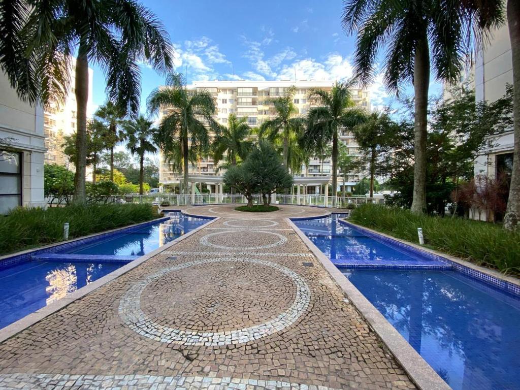 a resort pool with palm trees and a building at Barra Family Resort, a sua melhor escolha in Rio de Janeiro