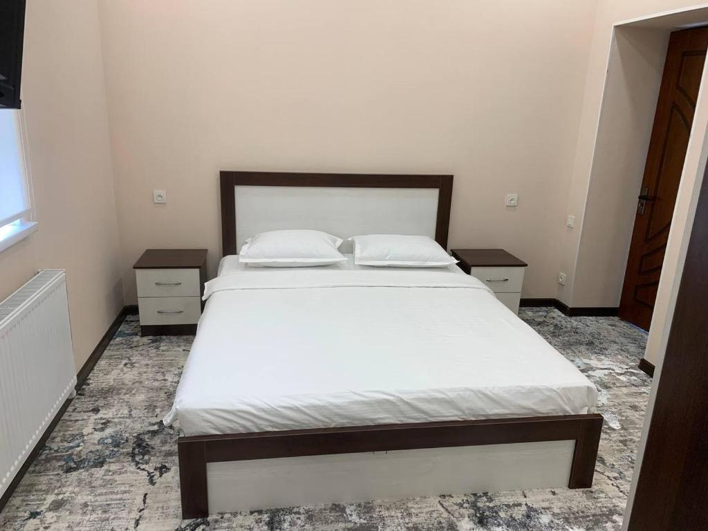 a bedroom with a bed with white sheets and two night stands at Islomobod in Tashkent