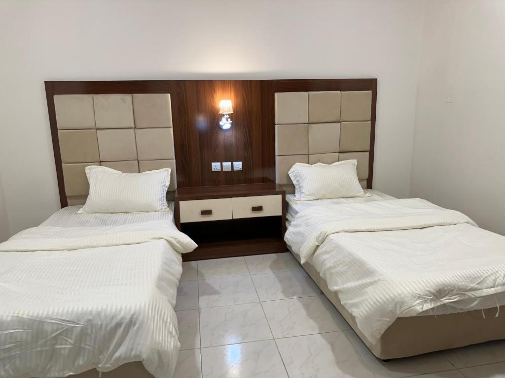 two beds in a room with white sheets at Dorat alsafaa in Hafr Al Baten