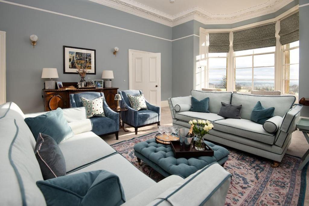 a living room with blue and white furniture and windows at Cairnbank House in Duns