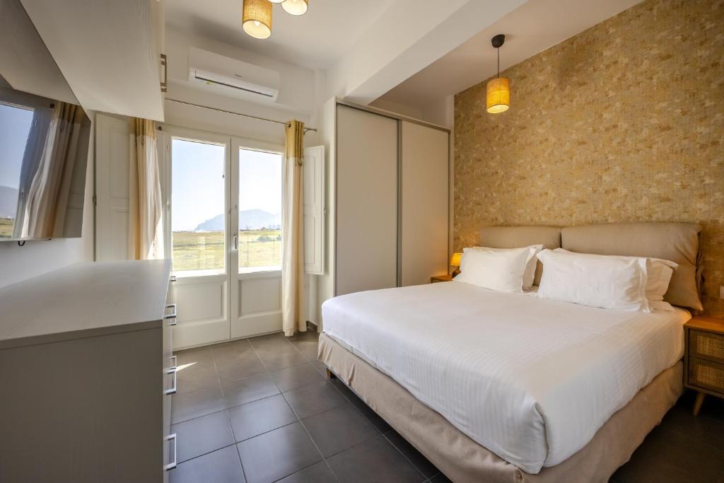 Un dormitorio con una gran cama blanca y una ventana en FN Suites, en Monolithos