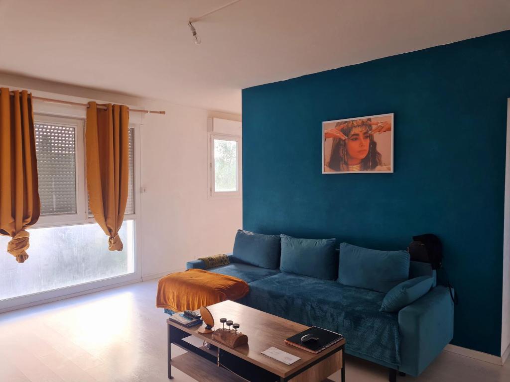 un salon avec un canapé bleu et une table dans l'établissement Logement entier appartement pas loin du circuit des 24, au Mans