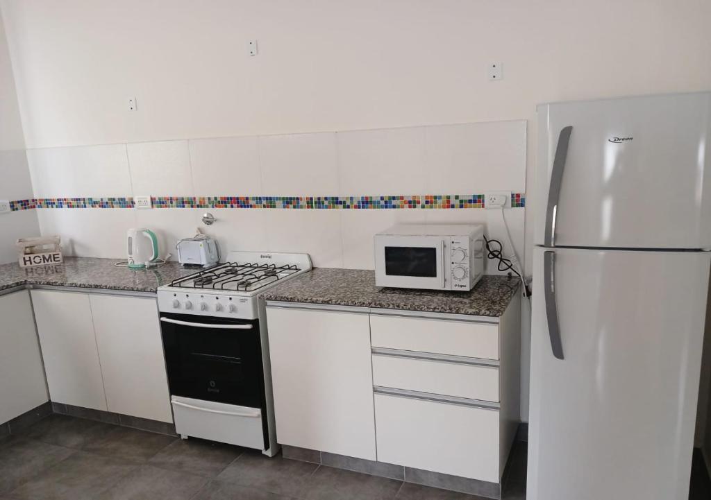a kitchen with a stove and a white refrigerator at Chacabuco Aparts in Chacabuco