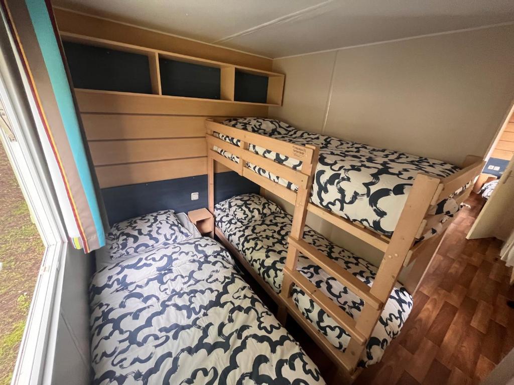 two bunk beds in a small room at Bungalow pour 5 - TV - Clim - Terrasse ensoleillée in Boofzheim
