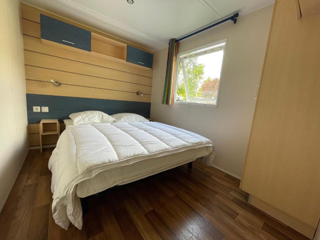 a bedroom with a large bed with a window at Bungalow pour 5 - TV - Clim - Terrasse ensoleillée in Boofzheim