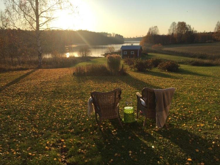two chairs sitting in a field next to a lake at Country house Ruohoranta in Kuopio