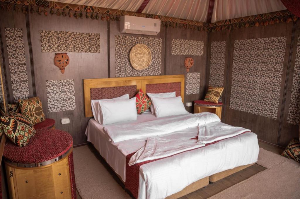 a bedroom with a large bed and two chairs at Desert Sand Camp in Wadi Rum