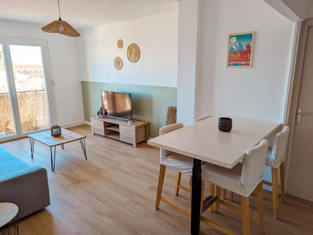 ein Wohnzimmer mit einem Tisch und einem Sofa in der Unterkunft Le Panoramique - T2 46m² - Proche centre-ville et gare in Perpignan