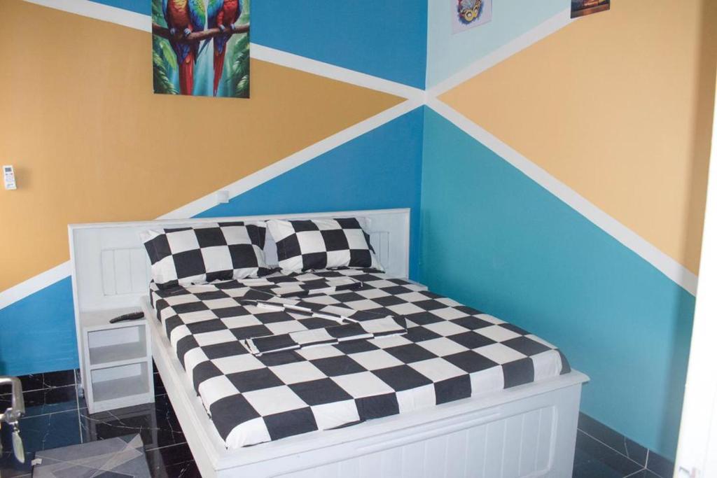 a bed in a room with a checkered wall at Studio Style Moderne in Pointe-Noire