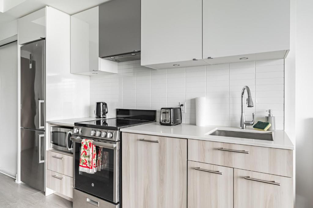 a kitchen with stainless steel appliances and white cabinets at Jarvis Apartment in Toronto