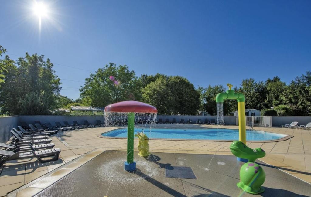 a swimming pool with a fountain and chairs around it at Bungalow pour 5 - TV - Clim - Terrasse ensoleillée in Boofzheim
