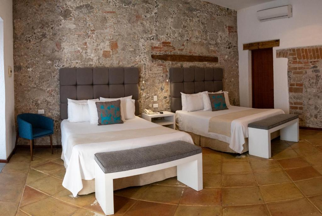 een slaapkamer met 2 bedden en een blauwe stoel bij Casa Pepe in Puebla