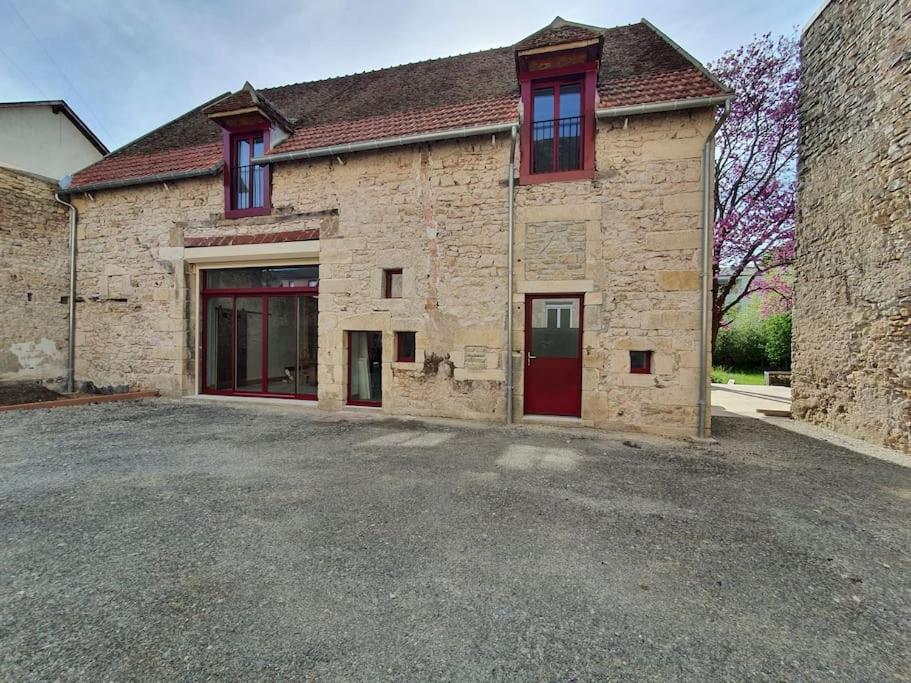 a large brick building with red doors on it at Gite de la grange 14 couchages in Saint-Amand-Montrond