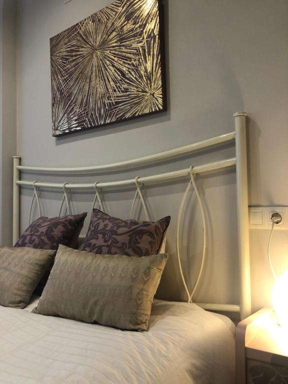 uma cama com almofadas e uma fotografia na parede em Tranquilo y acogedor piso con encanto em Vegadeo