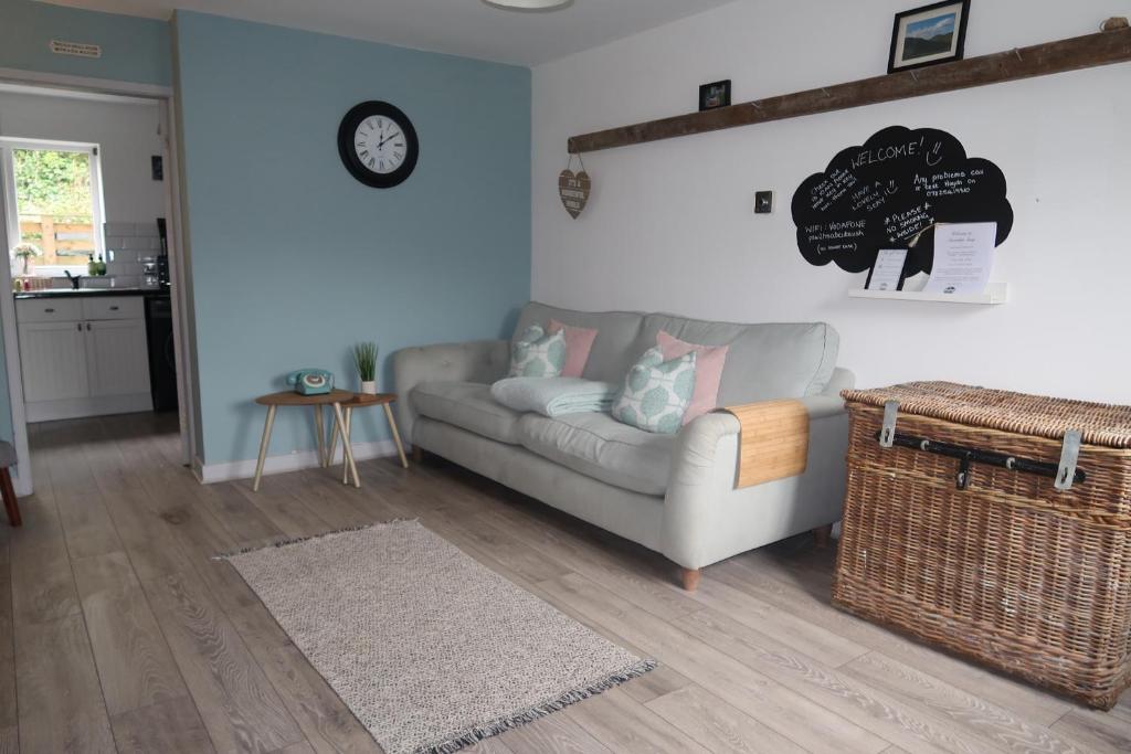 uma sala de estar com um sofá e um relógio na parede em Snowdon Snug em Llanberis