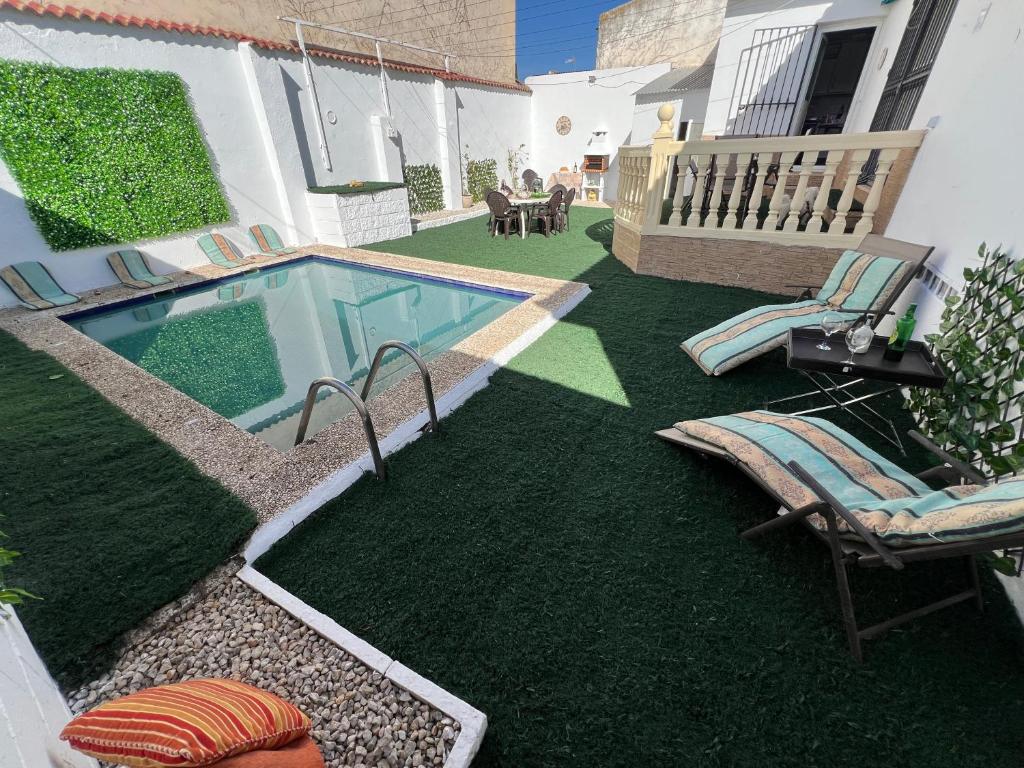 un patio trasero con piscina y césped con sillas en Casa Rural Las Eras de Campotejar, 