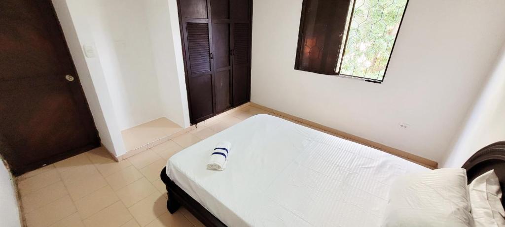 uma cama branca num quarto com uma janela em APARTAHOTEL HEFZIBA em Barranquilla