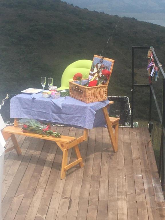 een picknicktafel met een mand op het dek bij TINY HOUSE LUJOSA CASA CON JACUZZI MALLA CATAMARAN in Guatavita