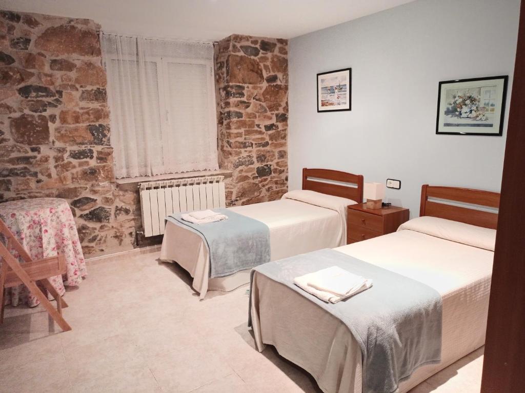a room with two beds and a stone wall at Agroturismo Biltegi Etxea 