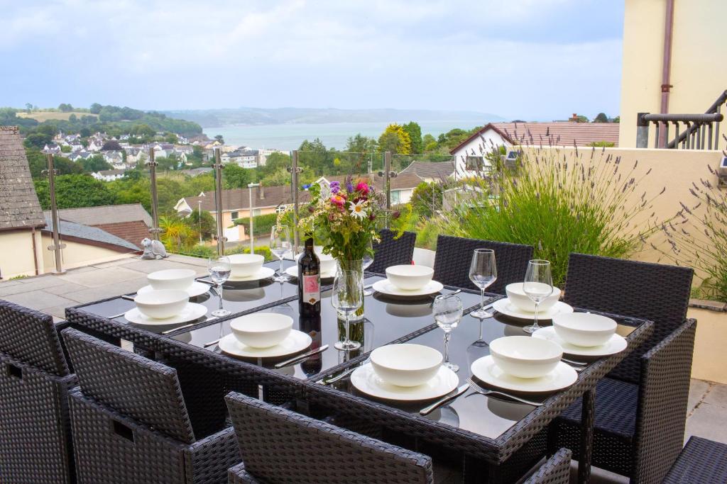 a table with plates and wine glasses on a balcony at Rooftops - Sea Views Near Village and Beach in Saundersfoot