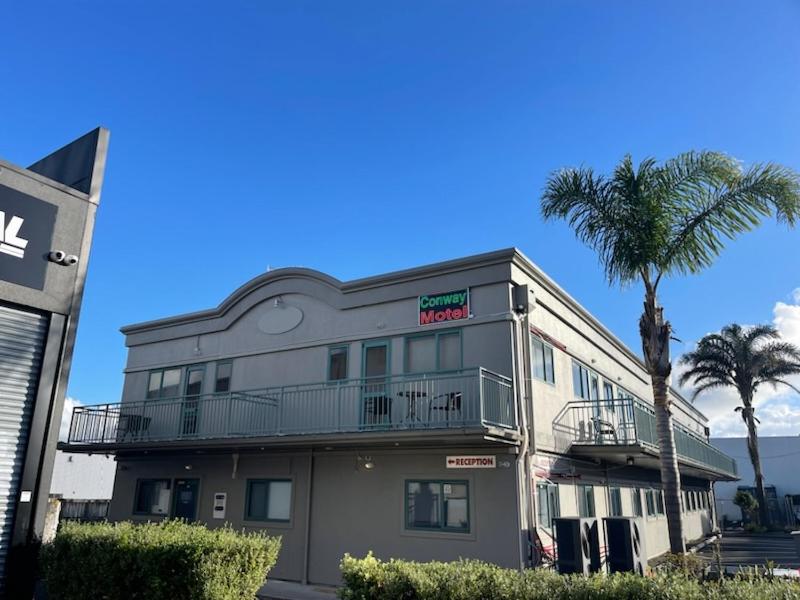 a building with a palm tree in front of it at Conway Motel Manukau in Auckland