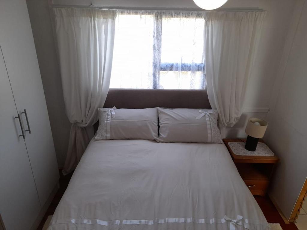 a bedroom with a white bed with a window at Megs Accommodation in Kamieskroon