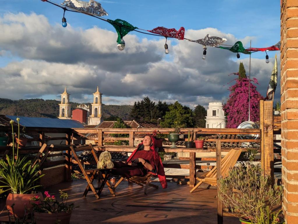 a woman sitting in a chair on a patio with a view at Casa Satoshi in San Cristóbal de Las Casas